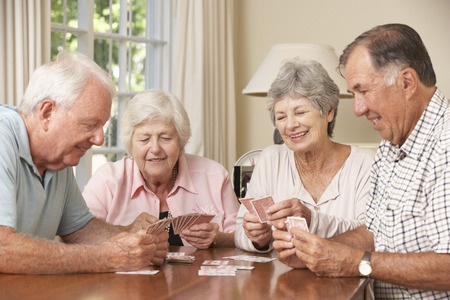 42164351 - group of senior couples enjoying game of cards at home